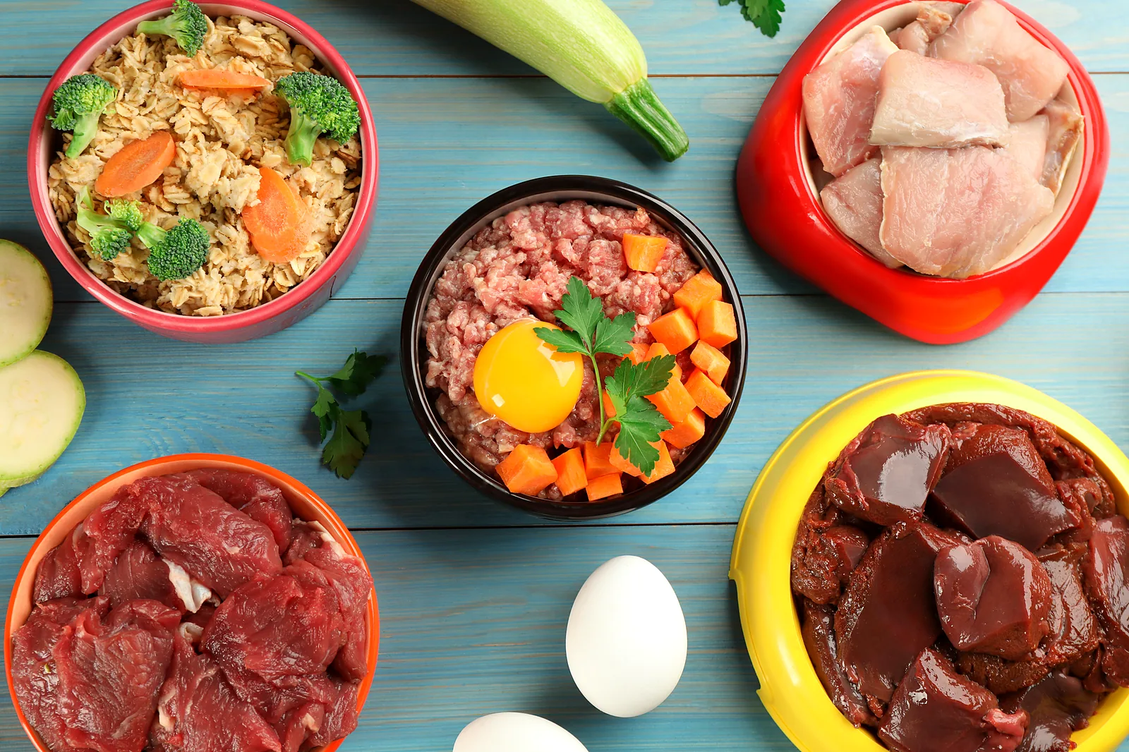 Bowls de colores con carne, pollo, huevo, arroz y vegetales frescos sobre una mesa azul